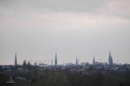 Graue Wolken über dem Stadtpanorama mit den Hauptkirchen St. Jacobi (vlnr), St. Petri, St. Katharinen, dem Rathausturm, der Hauptkirche St. Nikolai.