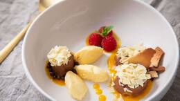 Dessert-Teller mit Schokoladen- und Mango-Mousse auf Mangopüree. Getoppt wird alles mit Eiswaffelsplittern, Schokoraspeln, Himbeeren und Minzblättern.