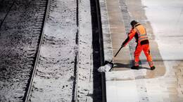 Ein Mann räumt am Morgen am Hauptbahnhof auf einem Bahnsteig am Hamburger Hapotbahnhof Schnee.