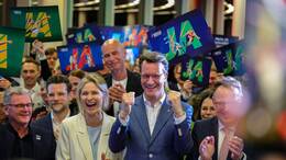 NRW-Ministerpräsident Hendrik Wüst (CDU, Mitte) und Kölns OB Torsten Burmester (r.) jubeln nach der erfolgreichen Abstimmung um die Olympischen Spiele in Nordrhein-Westfalen. Im Hintergrund: FC-Präsident Jörn Stobbe.